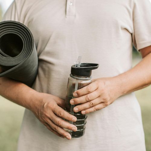 Yoga mat, water bottle and comfortable clothing prepared for a session.